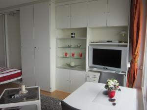 ein weißes Wohnzimmer mit einem TV und einem Tisch in der Unterkunft Ferienwohnung-Apartment-Seeblick-in-Plaza-Marit-Residenz in Timmendorfer Strand