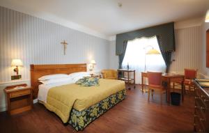 a hotel room with a bed and a table and chairs at Hotel Centro di Spiritualità Padre Pio in San Giovanni Rotondo