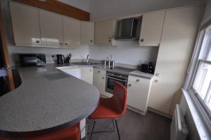 a kitchen with white cabinets and a counter with a red chair at Princes Dock Chambers 9 in Hull