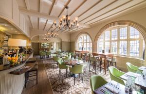 un ristorante con sedie verdi, tavoli e finestre di The Crown Manor House Hotel a Lyndhurst