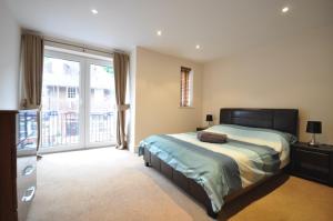 a bedroom with a bed and a large window at Letting Serviced Apartments - Chorleywood Village in Chorleywood