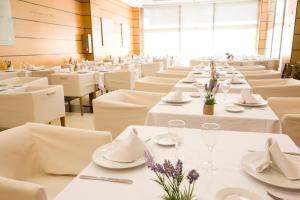 un comedor con mesas blancas y sillas blancas en Hotel Albufera, en Alfafar