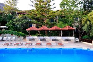 a swimming pool with chairs and tables and umbrellas at Elpida Village in Istro