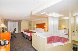 a hotel room with a tub and a bed at Ramada by Wyndham Niagara Falls by the River in Niagara Falls