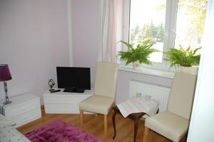 a living room with three chairs and a television at Koral Dom Gościnny in Koszalin