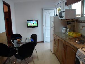 a kitchen with black chairs and a table with a tv at MarWal Departamentos in Santa Teresita
