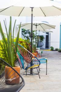 a pair of chairs under an umbrella next to plants at Gente de Más Bnb in Puebla