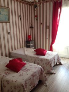 IlliersにあるDomaine de Montjouvinのベッドルーム1室(赤い枕のベッド2台付)