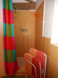 a bathroom with a rainbow shower curtain and two chairs at Petit Grenier Douillet De Cathie in Roquemaure