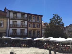 un edificio con mesas y sombrillas blancas delante de él en Santiago 31 Hostel, en Guimarães