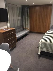 a bedroom with a bed and a couch and a dresser at Carlton Hotel in Ilfracombe