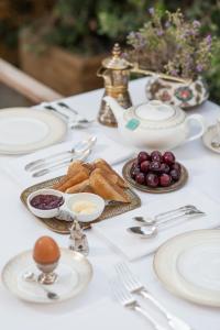 una mesa blanca cubierta con platos y utensilios de plata en La Maison Ottomane, en La Canea