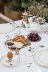 a white table topped with plates and silver utensils at La Maison Ottomane in Chania Town
