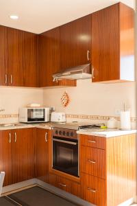 uma cozinha com armários de madeira e um forno com placa de fogão em CASAL RIQUEZO T1 - Serra da Pescaria - NAZARÉ na Nazaré