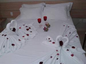 Teodoro SampaioOnix Inn Hotel的一张带白色床单和酒杯的床
