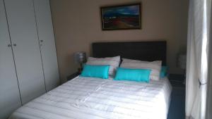 a bedroom with a bed with blue and white pillows at La Palma Villas in Mossel Bay