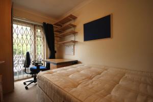 1 dormitorio con cama, escritorio y ventana en Draycott en Londres