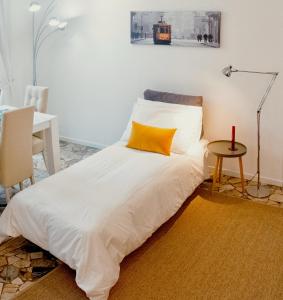 ミラノにあるDe Amicis Apartment Near Duomoの白いベッド(黄色い枕、テーブル付)