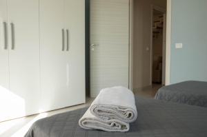 Una toalla blanca sentada en una cama en un dormitorio en Bosco Sea Apartments, en San Leone 50 fotos más