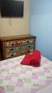een rood kussen op een bed met een tv aan de muur bij Pousada da Guarda in Guarda do Embaú