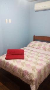 um quarto com uma cama com um cobertor vermelho em Pousada da Guarda em Guarda do Embaú