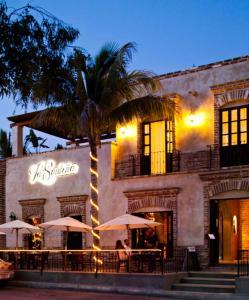 a palm tree in front of a building with umbrellas at Hotel Casa Tota in Todos Santos