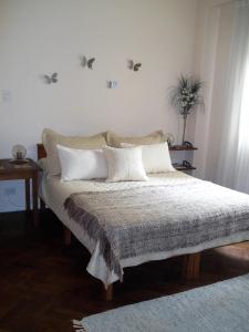 1 cama con almohadas blancas y pájaros en la pared en Departamento Posadas en Buenos Aires