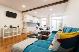 ein Wohnzimmer mit einem blauen Sofa und einer Küche in der Unterkunft FLH Graça Artistic Studio in Lissabon