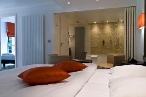 a bedroom with a bed with two pillows and a bathroom at Cocoon Hotel Belair in Bourscheid