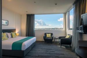 a hotel room with a bed and a large window at Quest Henderson Serviced Apartments in Auckland
