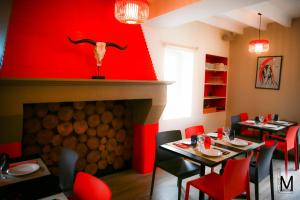 a dining room with a fireplace and red walls at Au Coeur Des Landes in Gaillères