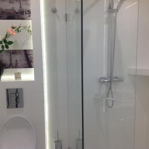 a white bathroom with a shower and a toilet at Apartament Horyzont in Międzyzdroje