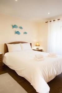 ein Schlafzimmer mit einem großen weißen Bett mit Fisch an der Wand in der Unterkunft CASAL RIQUEZO T2 - Serra da Pescaria - NAZARÉ in Nazaré