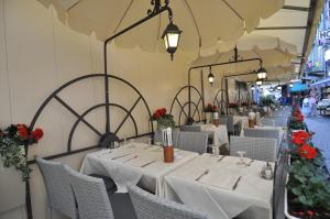 um restaurante com mesas brancas, cadeiras e flores em Hotel Moderno em Stresa