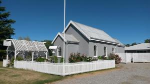 a small church with a white fence in front of it at St Andrews Church Vestry in Ophir