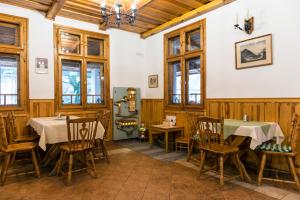 a dining room with tables and chairs and windows at Rácz Fogadó in Kisoroszi