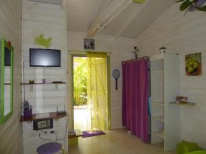 a room with a door and a tv and a table at Coco Bungalows in Sainte-Rose