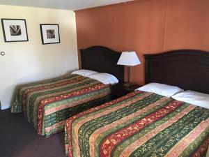 a hotel room with two beds and a lamp at Angola Motel in Angola-on-the-Lake