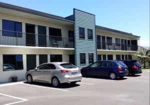 two cars parked in a parking lot in front of a building at ASURE Abode On Courtenay Motor Inn in New Plymouth