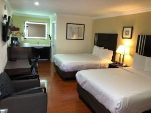 a hotel room with two beds and a chair at Lombard Plaza Motel in San Francisco