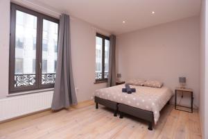 Un dormitorio con una cama y dos grandes ventanales. en Parlamentarium apartment, en Bruselas 28 fotos más