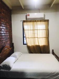 a bedroom with a bed with a brick wall and a window at Rareheart Guesthouse in Kuala Terengganu