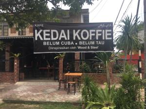 a sign for a restaurant with a table and chairs at Rareheart Guesthouse in Kuala Terengganu