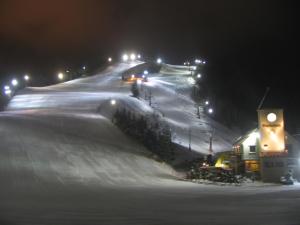 a snow covered hill at night with lights on at Biwaike Hotel in Yamanouchi +3 photos