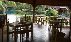 a restaurant with tables and chairs on a porch at Cliff Side Beach Resort and Cottages in Lomangcapan