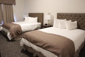 Habitación de hotel con 2 camas con sábanas blancas en Prairie Moon Inn & Suites Macklin, en Macklin