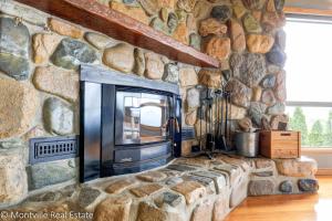 a stone wall with a fireplace in a living room at Magnolia in Maleny