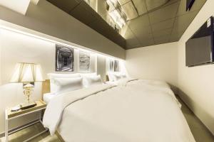 a bedroom with a large white bed and a lamp at Darak Hotel in Seoul