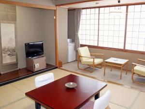 a living room with a table and chairs and a tv at Hotel Kameya in Osaki