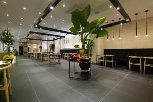 a restaurant with tables and chairs and a plant at Hotel The Designers Incheon in Incheon